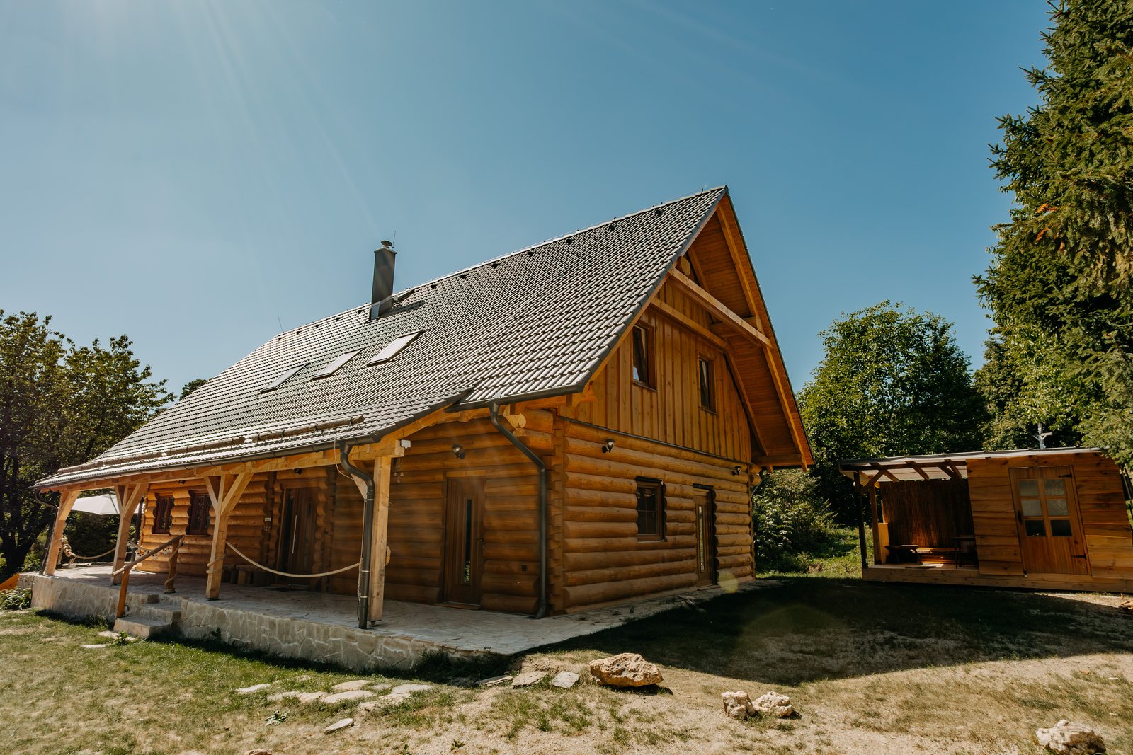 Boční pohled na roubenku s podkrovními okny a zelení Jeseníků kolem