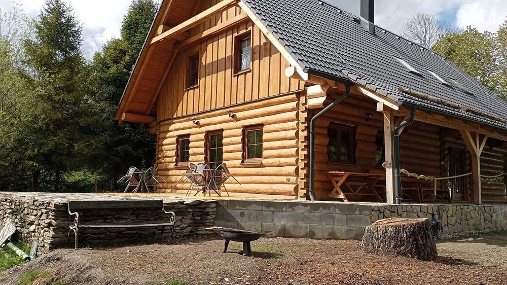 Boční pohled na roubenku s posezením na terase a zelení kolem