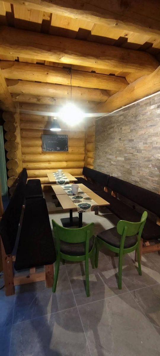 Jídelna s dlouhým stolem a lavicemi pod trámovým stropem