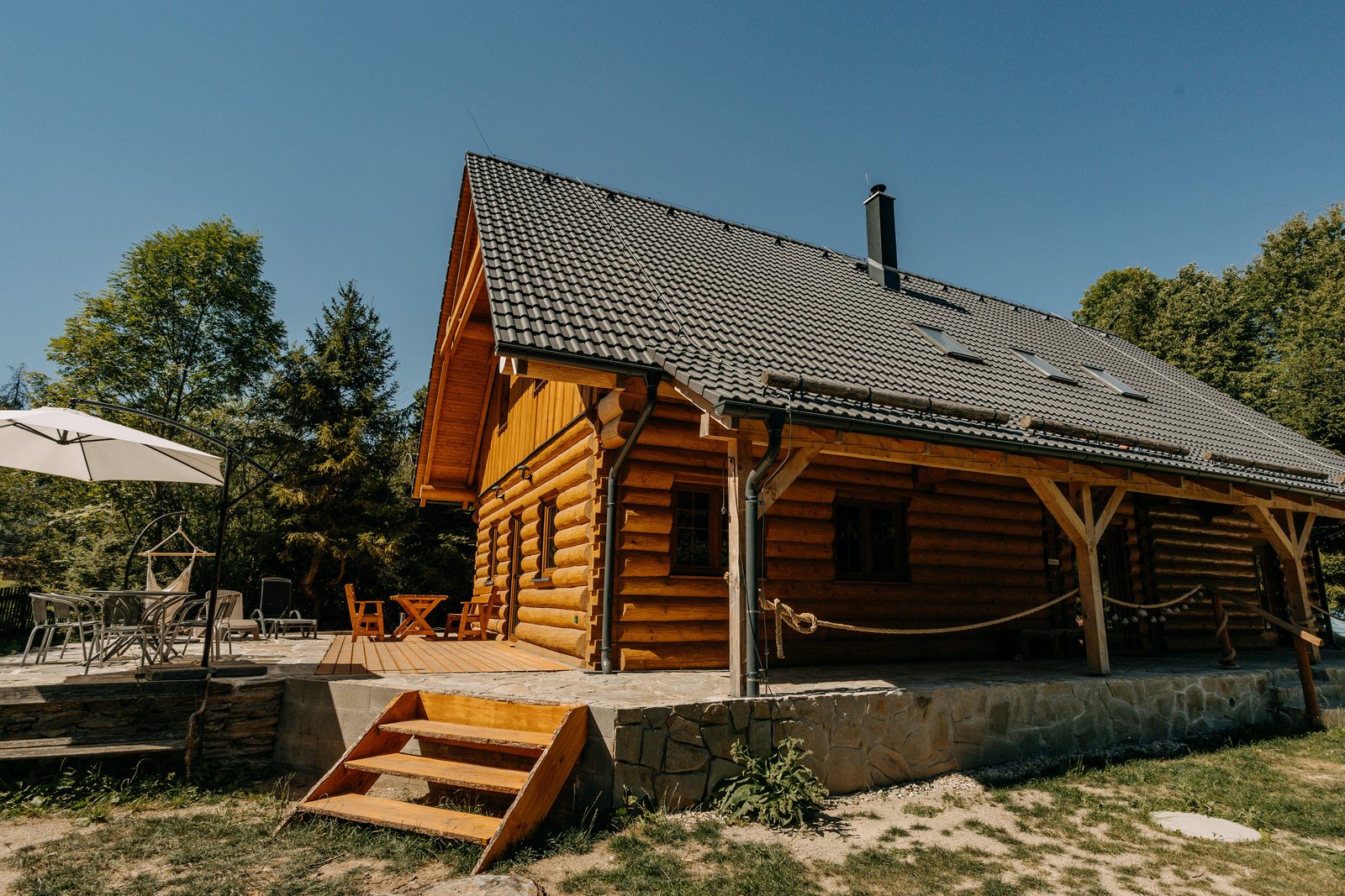 Boční pohled na roubenku se schody na terasu a slunečníkem